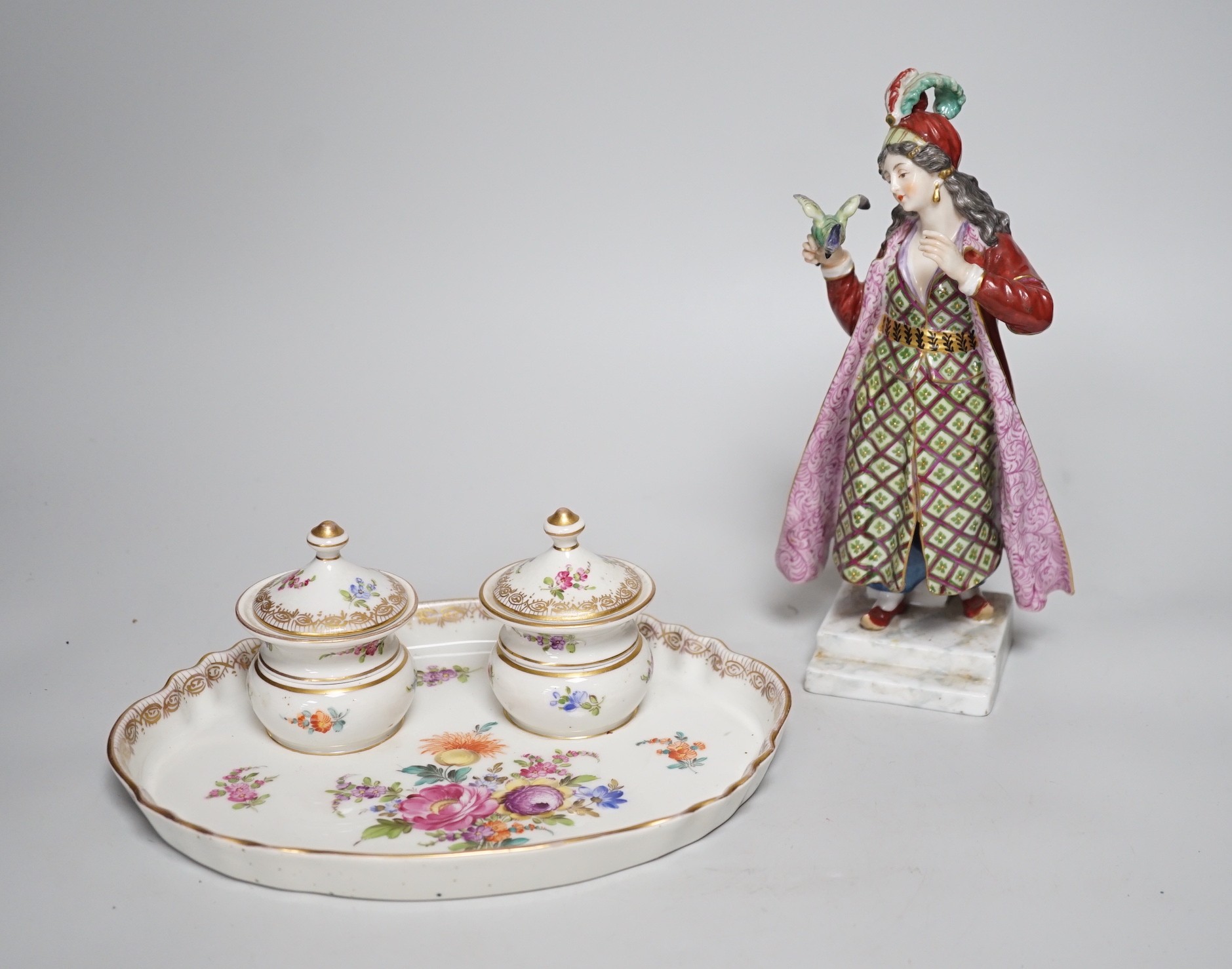 A 19th century German Inkstand with two pots and covers painted with flowers, 24cm wide, and a Volkstedt figure of an eastern European woman holding a bird	